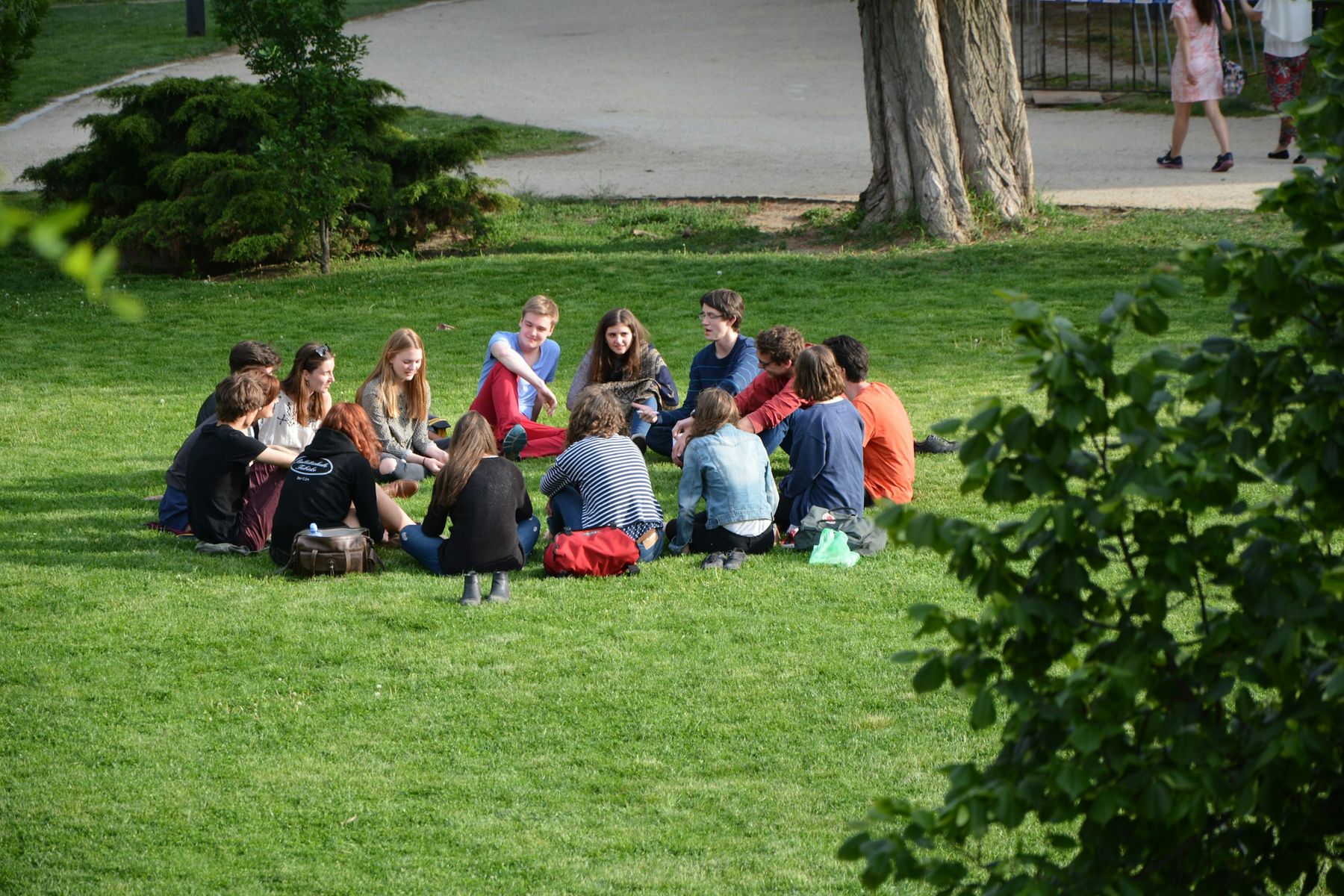 Un groupe assis en cercle sur la pelouse du parc, en pleine discussion