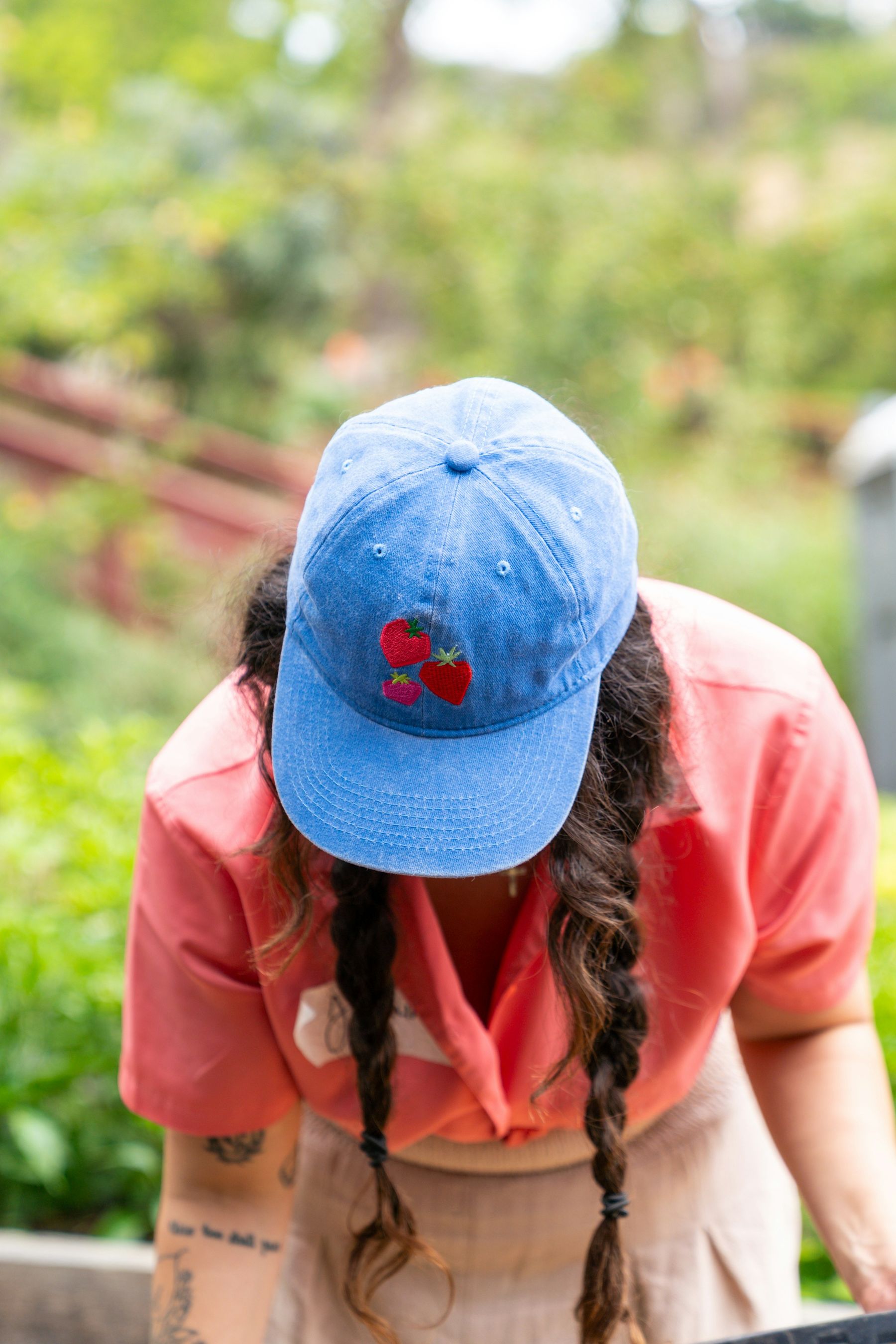 Une bénévole penchée sur une jardinière, casquette brodée de fraises